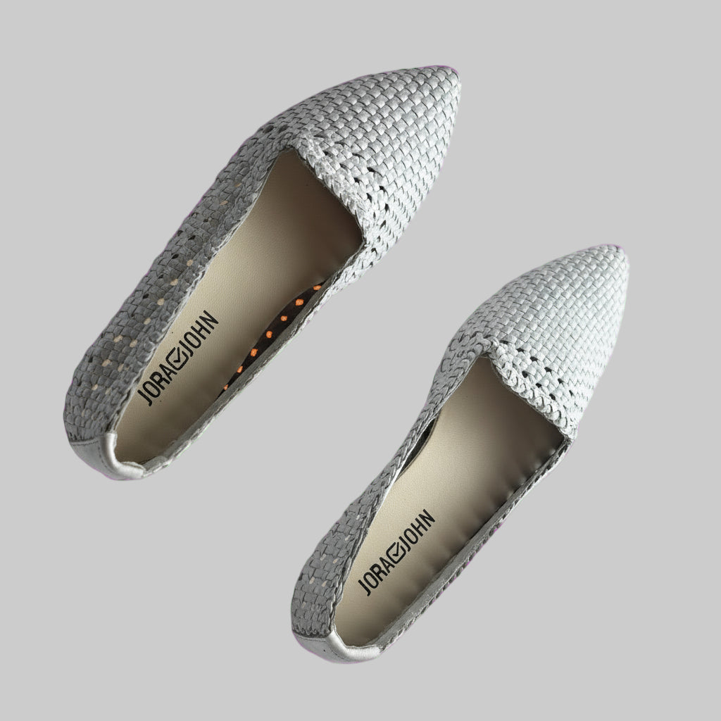 Pair of gray pointed-toe shoes on a pink background