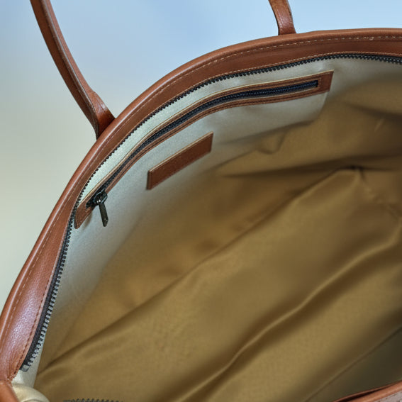Open brown leather handbag with a visible interior.
